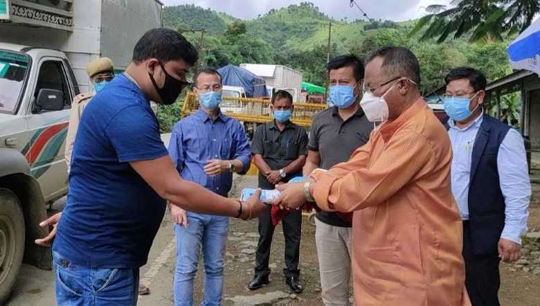 Health Minister Jayantakumar Singh (R) hands over medical kits for truck drivers at Keithelmanbi along the Imphal-Jiribam road on August 17, 2020
